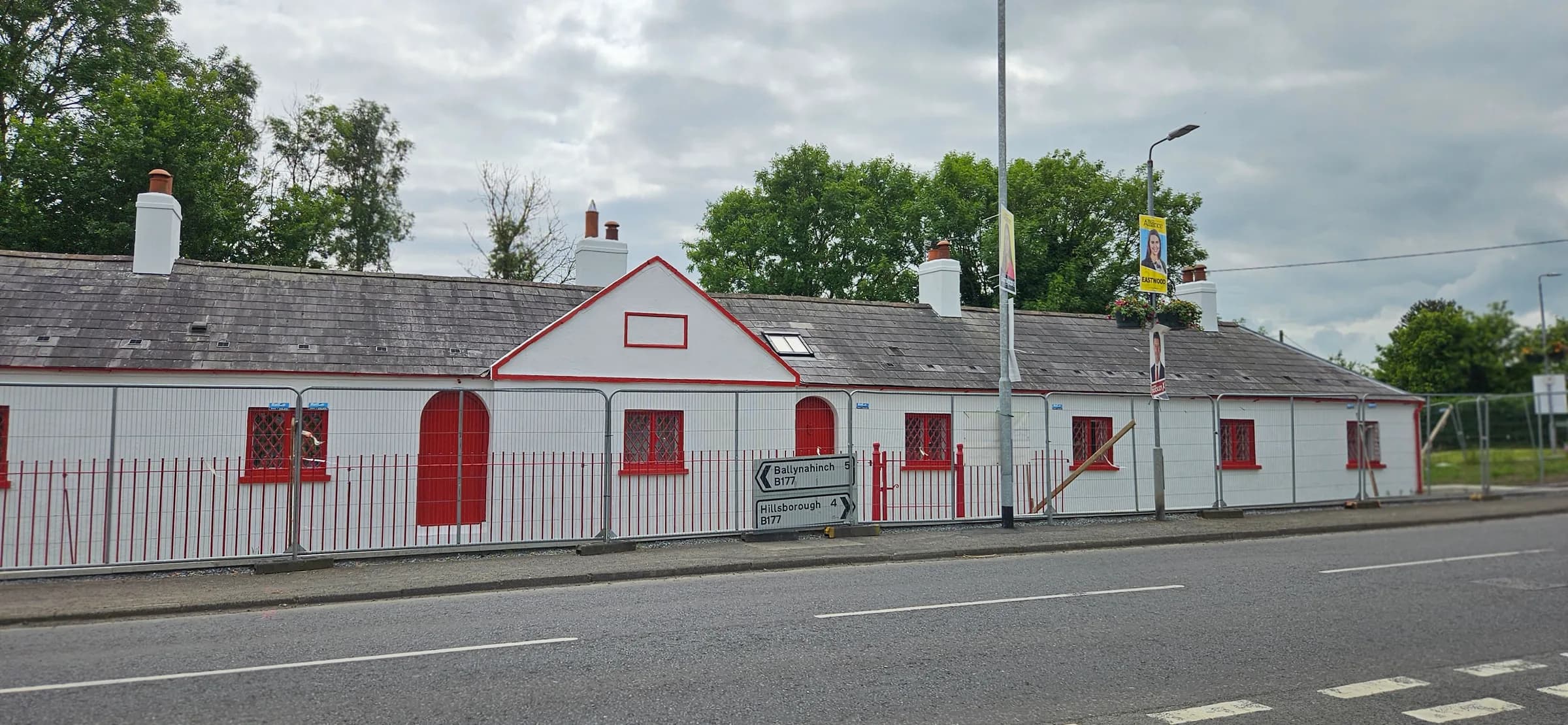 The finished terrace in white with red joinery, a red arched door and red railings along the roadside