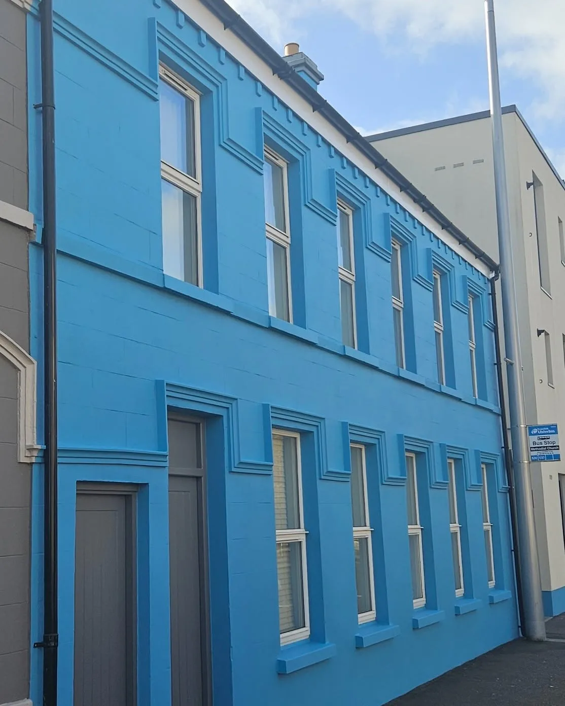 The finished terrace in bright blue with white sash surrounds against a clear sky
